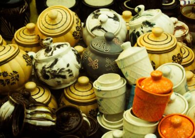 Variety of ceramic jars with lids in different colors and patterns in a market setting.
