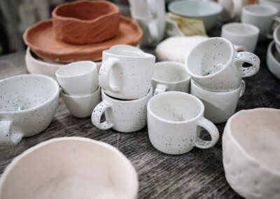 Close-up of artisan pottery cups and bowls arranged on a rustic table.