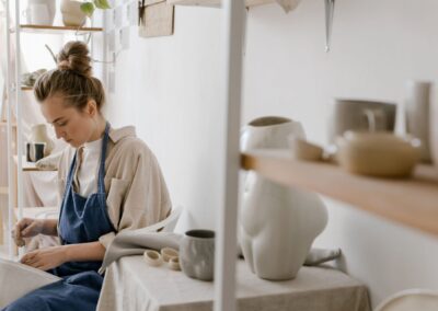A woman artist carefully crafting pottery in a bright, modern ceramic studio.